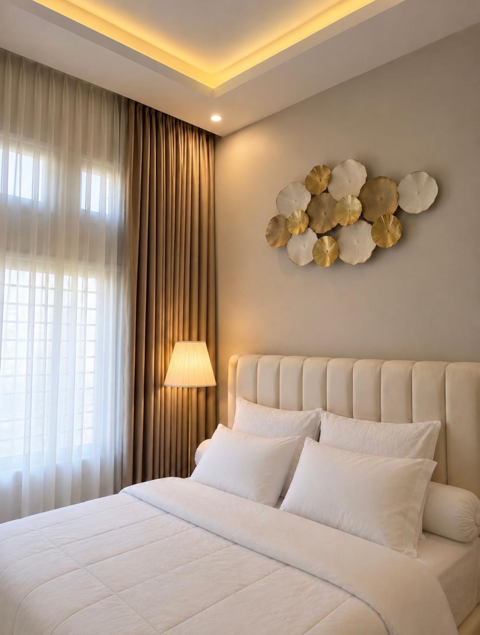 Kamar tidur dengan gorden taupe, vitrase putih, dan hiasan dinding logam